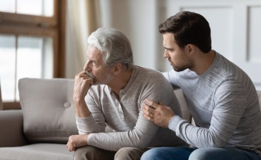 Loving young man embrace comfort upset elderly gray-haired dad suffering from depression or problems