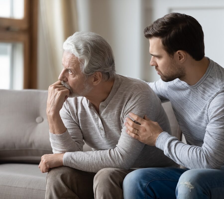 Loving young man embrace comfort upset elderly gray-haired dad suffering from depression or problems