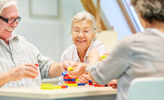 A group of seniors stacking small blocks to practice manual dexterity in an independent living community.