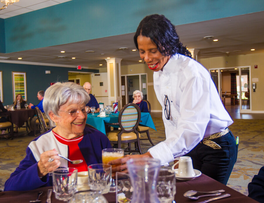 A senior woman is served a beverage in the dining room