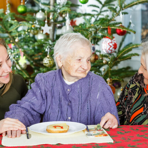 Two daughters celebrate the holidays with elderly parents at assisted living community.