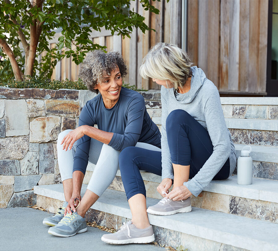 Two active senior ladies tying their shoes and getting ready to go out for a run