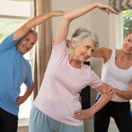 Exercise is just one way of improving quality of life for seniors. Here, a senior man and senior woman work with a trainer in an exercise class.