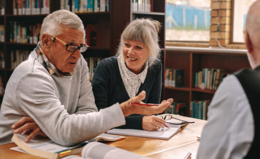 Seniors taking part in lifelong learning discussing topics in a library