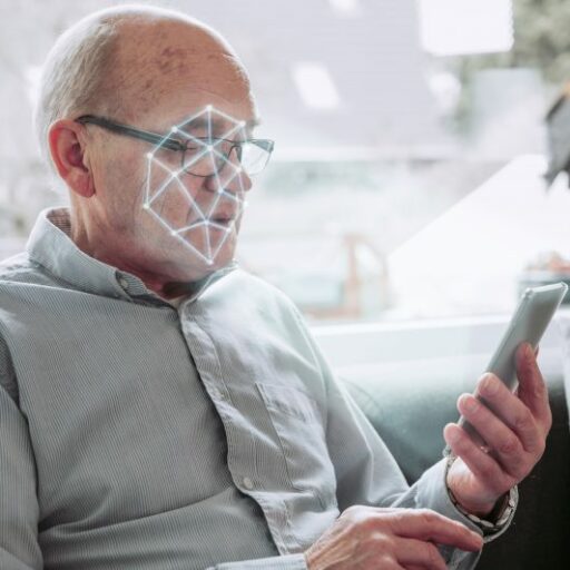 There is a lot of research about AI and aging happening now. Here, a man holds up his smart phone as it scans his face.
