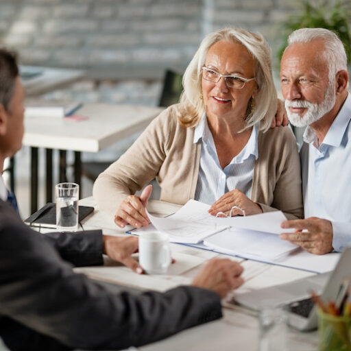 Happy senior couple talking with elder law attorney while analyzing documents on a meeting in the office.