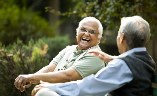 Two senior men being socially active on park bench