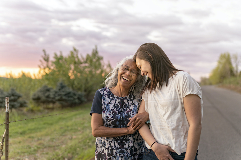 A young woman and older woman go for a walk around sunset, which is assisting the older woman in aging with grace.