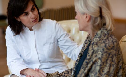 An adult woman cares for her mother, a senior with dementia.