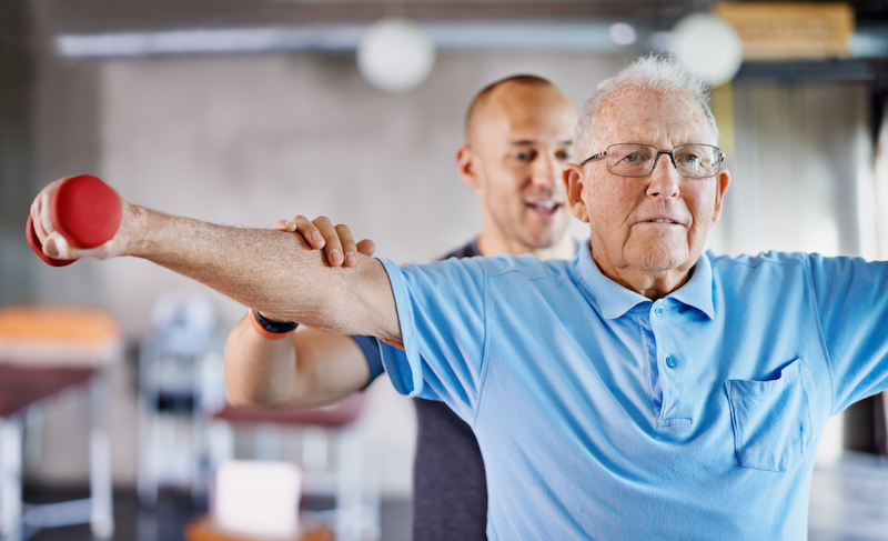 Trainer assisting senior man with workout and senior fitness goals