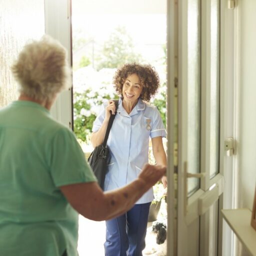 A caregiver meets a senior woman at her front door for in-home respite care services.