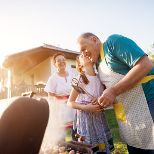 Senior man grilling with family at summer barbecue