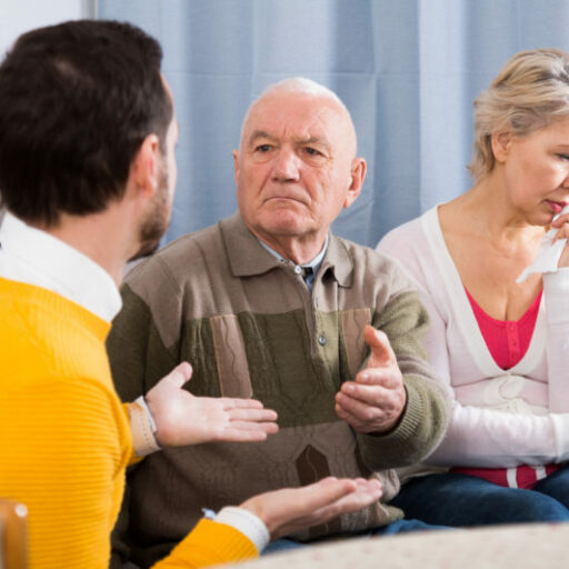 An adult man talks with his senior father and mother about aging. Talking to your parents about aging can be a difficult conversation, as pictured here.