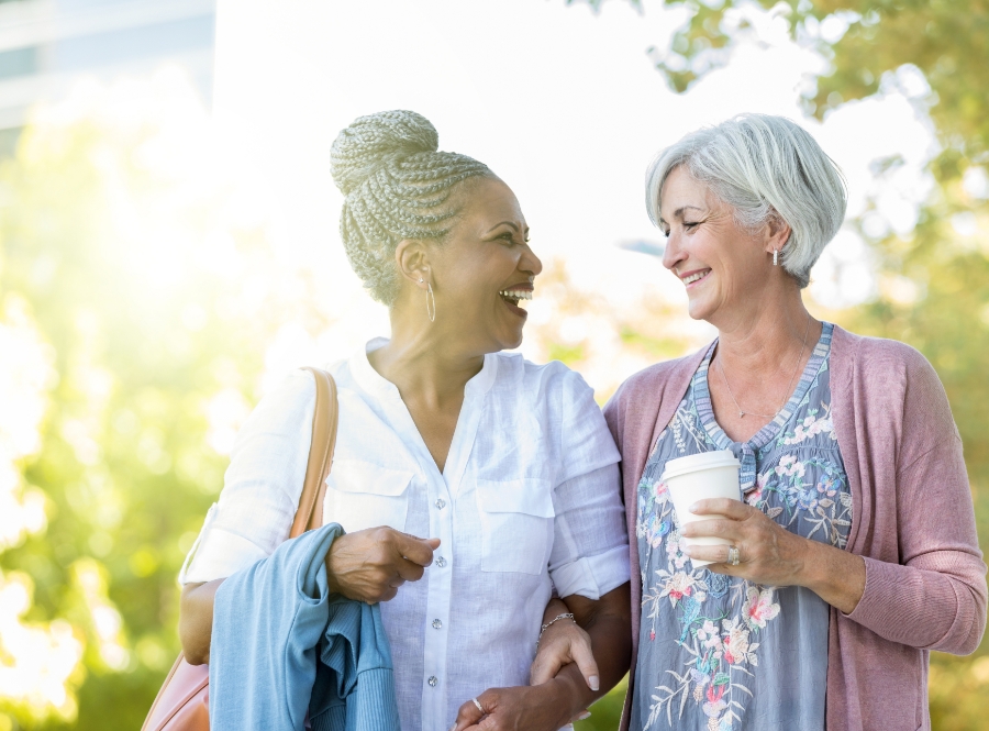 Two senior women walking hand and hand talking and smiling