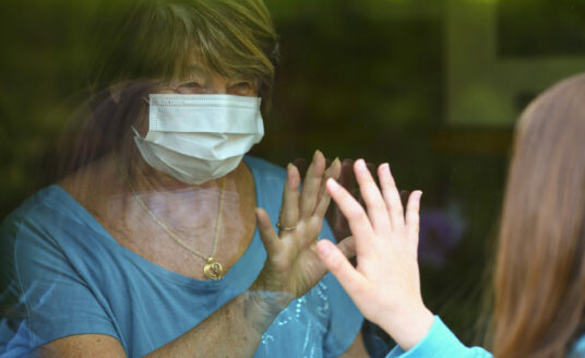 Senior practicing social distancing during visit from granddaughter